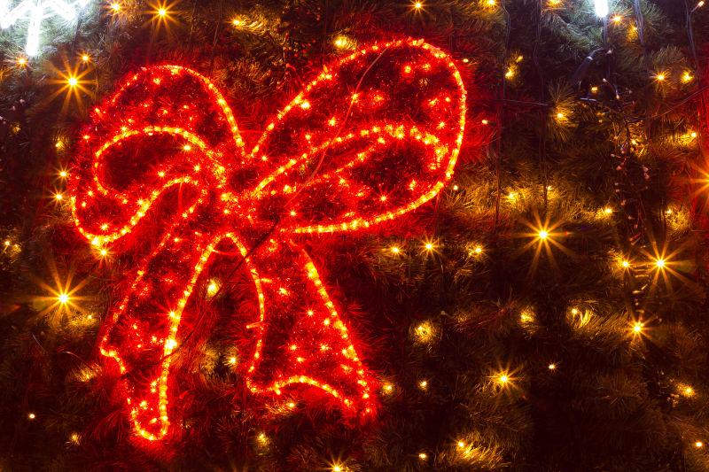 黑色背景上圣诞树上彩灯组成的蝴蝶结