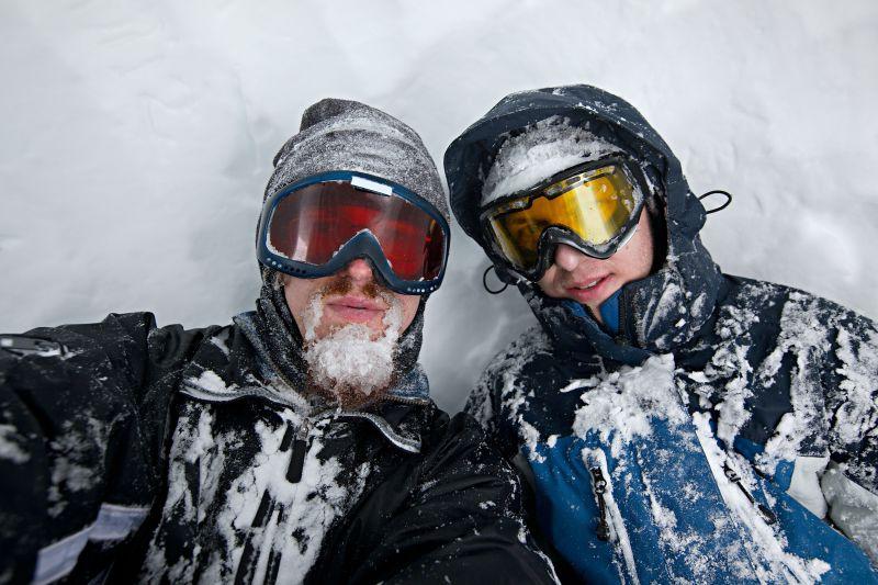 白色背景上躺在雪地上带着护目镜的男人们