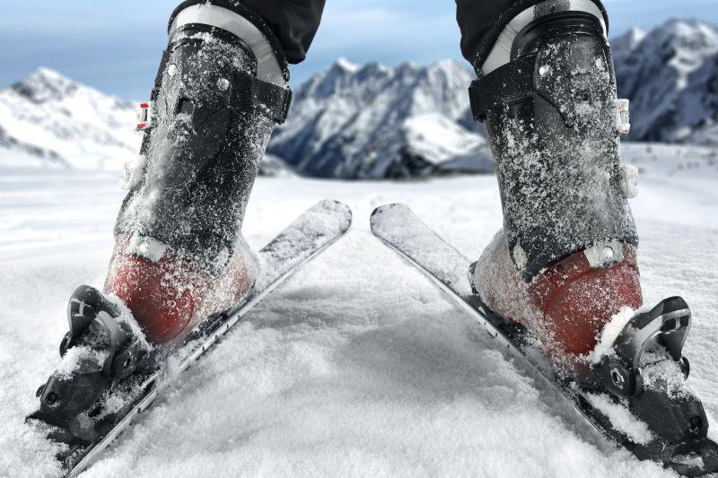 蓝天下雪山背景上的滑雪者的脚部