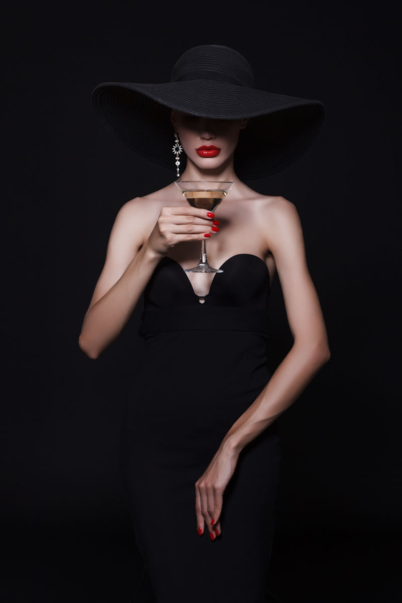 穿着黑色礼服的女人拿着红酒杯
