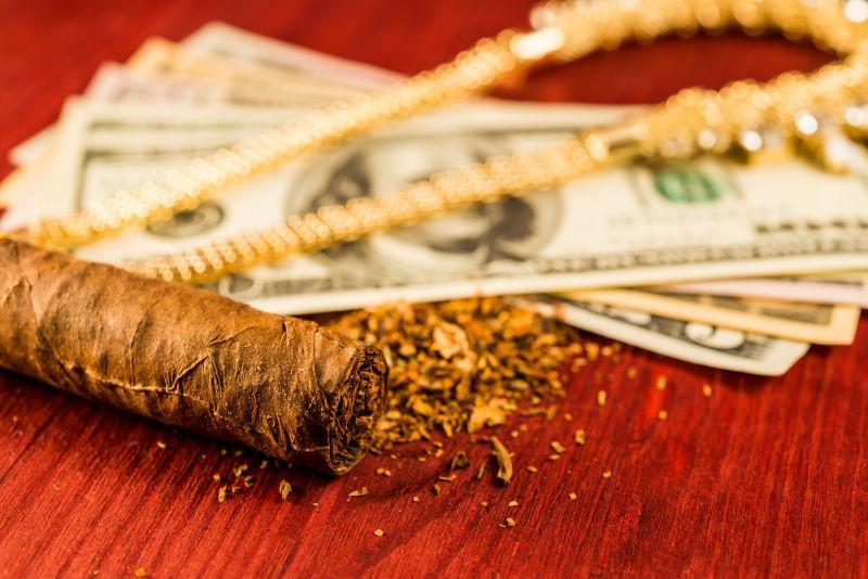 木桌上的美元纸币雪茄和珠宝