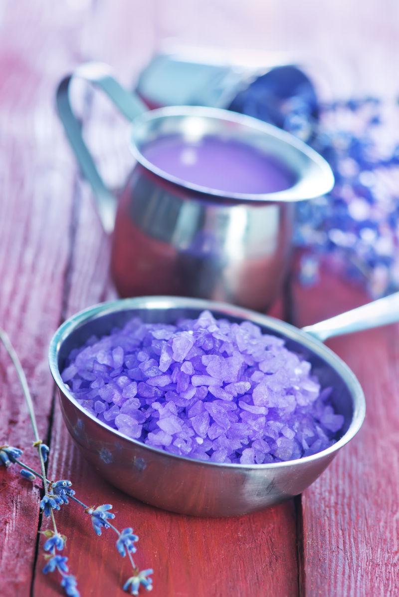 木桌子上金属碗里的紫罗兰浴盐