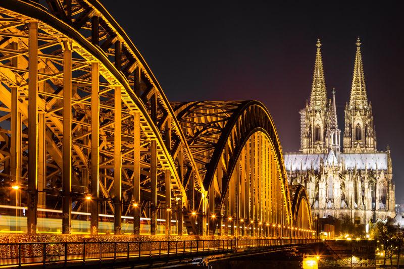 夜晚亮起黄色灯光的科隆大教堂旁的霍亨索伦桥