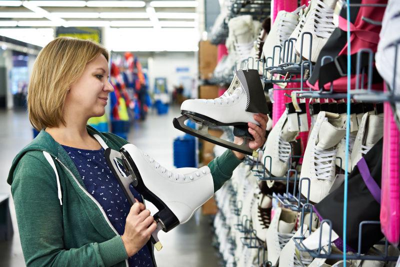 女子在体育用品店里选购花样滑冰鞋