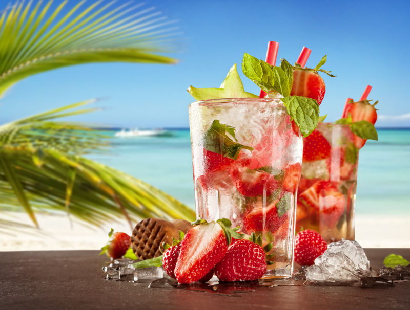海边沙滩上放着草莓与草莓饮料