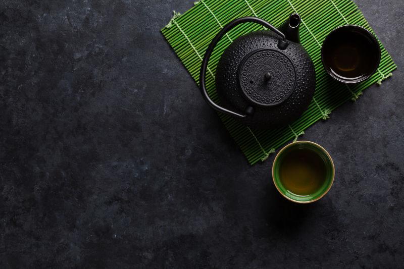 石桌上的绿茶杯和茶壶