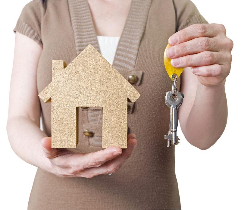 女人手上的房子模型和钥匙安全概念