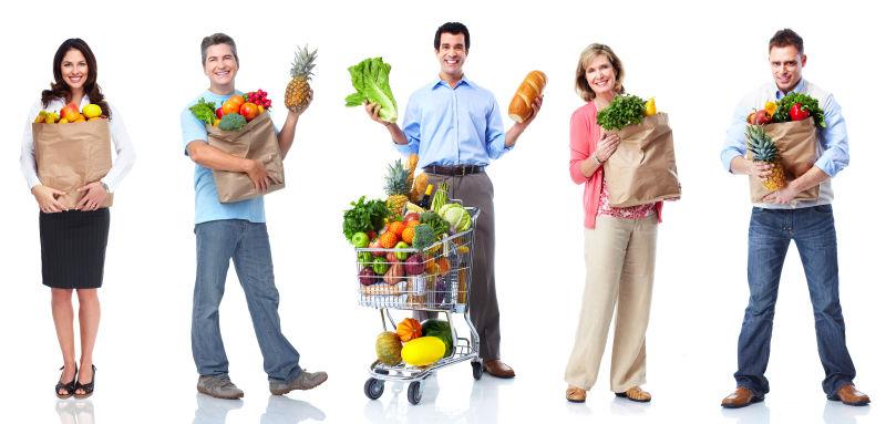 在白色背景下年轻的人们抱着新鲜的蔬菜和水果