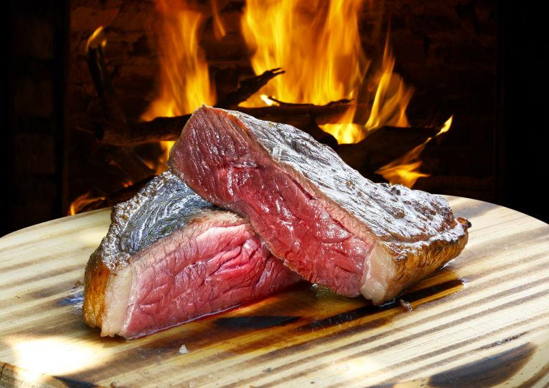 有火焰的背景下的木板上的未熟的烤肉