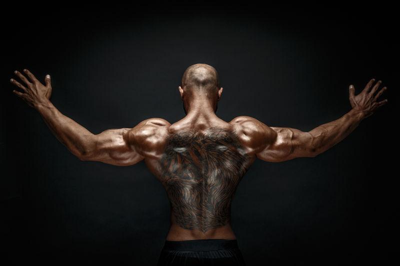 纹身的肌肉男人在黑色背景下