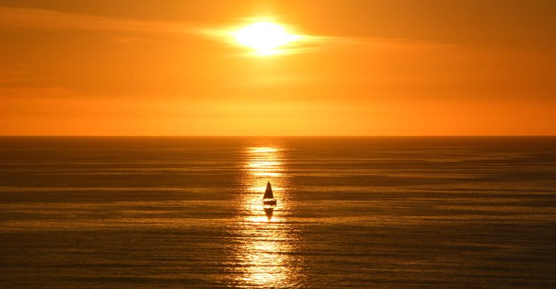 落日余晖下的海面上飘着一艘小船