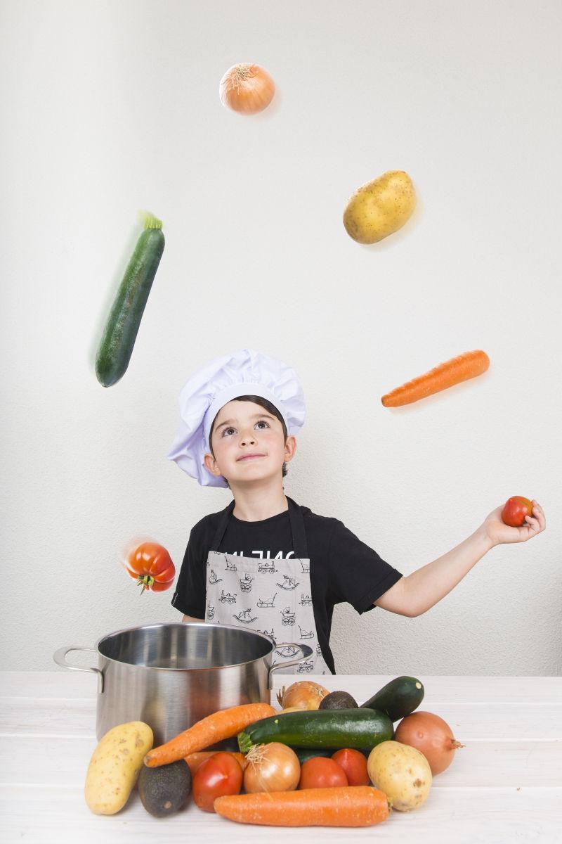 小厨师在厨房用蔬菜玩杂耍