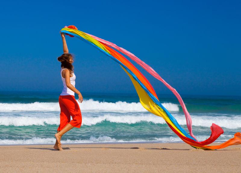 沙滩上挥舞着彩色丝带的美女
