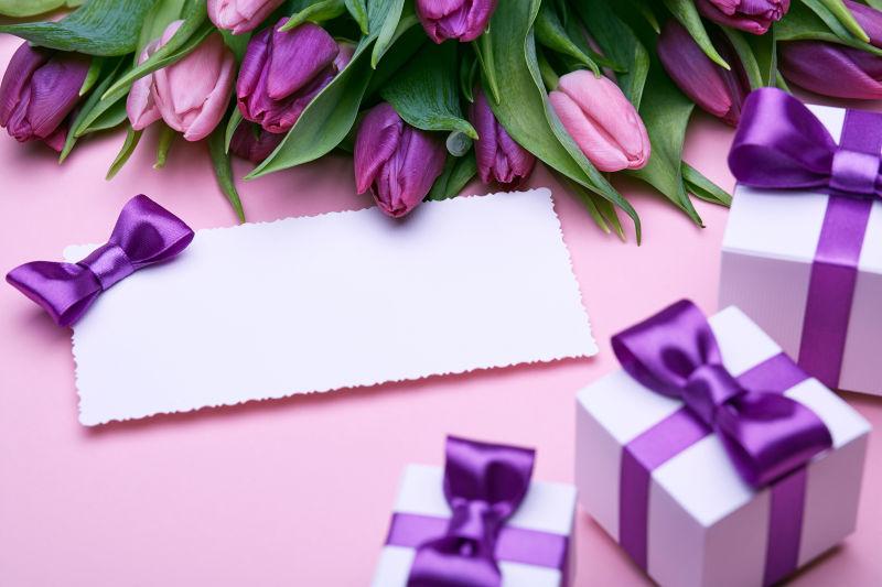粉色背景的礼物盒紫色郁金香和信封