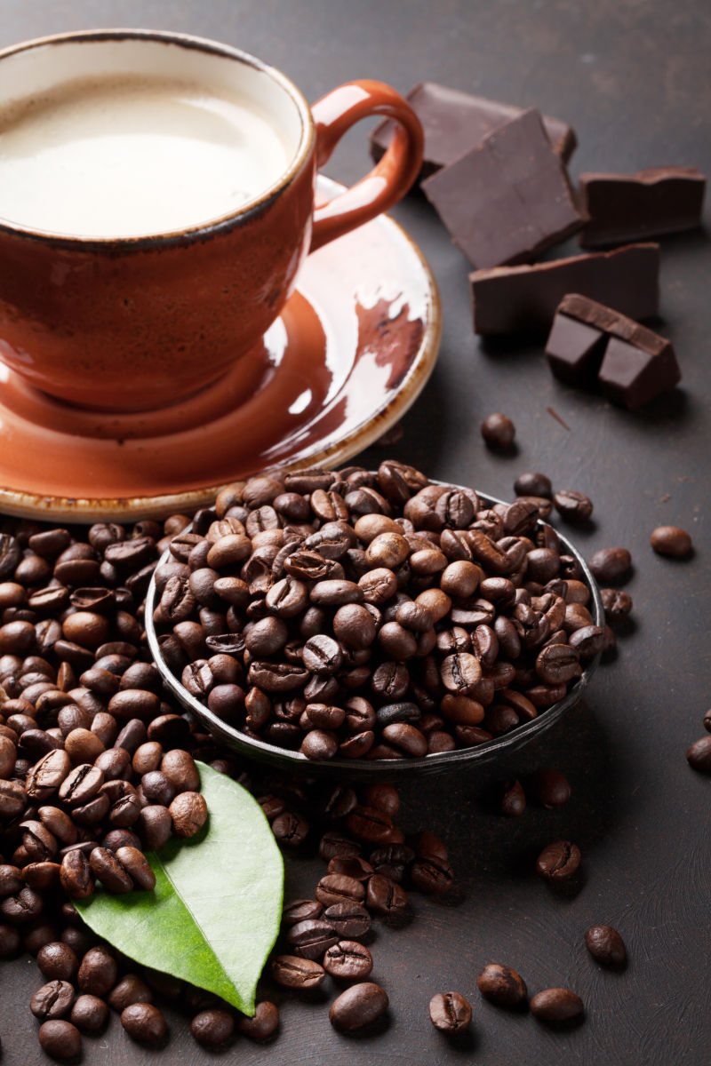 咖啡豆旁的一杯咖啡和黑巧克力