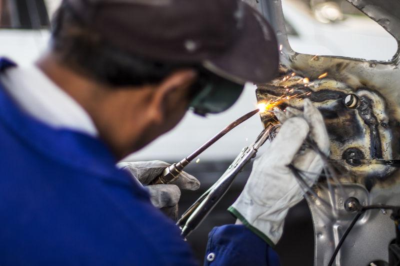机械工人使用焊棒修理汽车