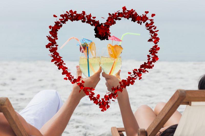年轻情侣在沙滩上拿着鸡尾酒