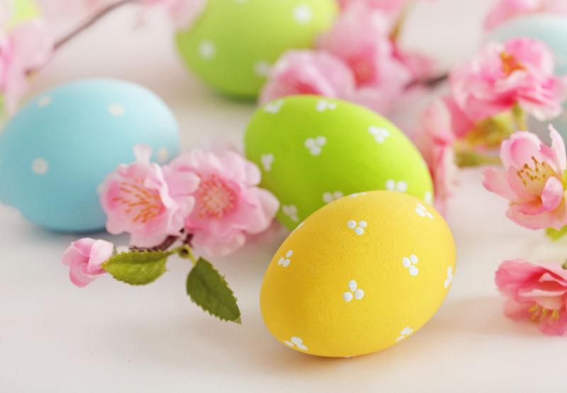 白色桌子上的复活节彩蛋和粉色花朵