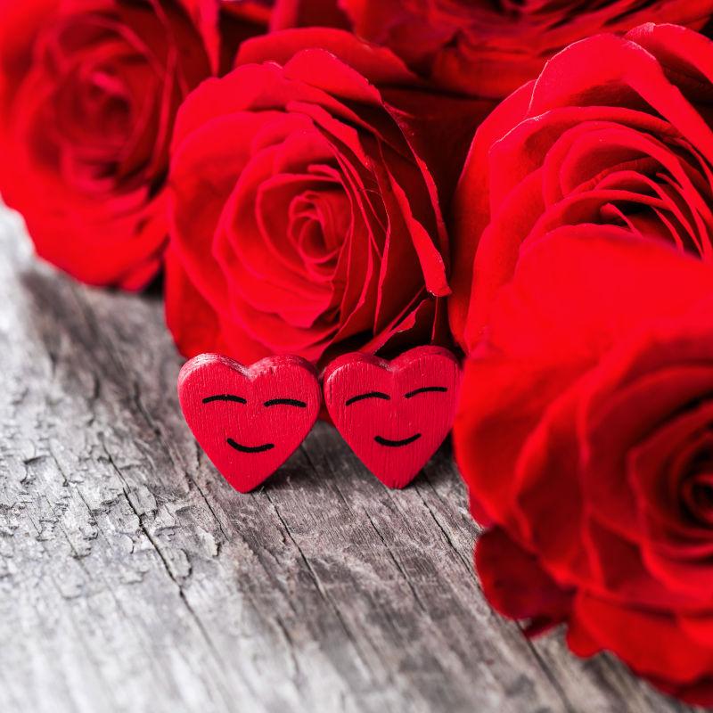木制背景下的红玫瑰和两颗微笑的心