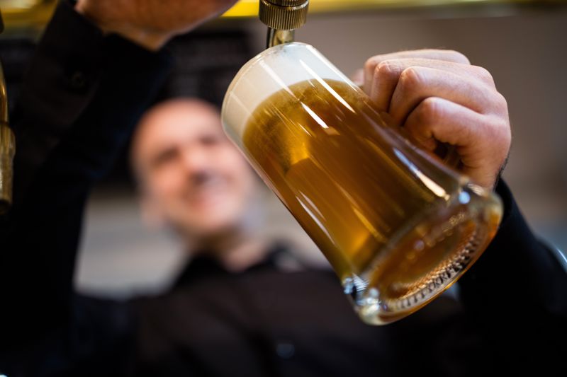 男人拿着杯子在啤酒龙头前接啤酒