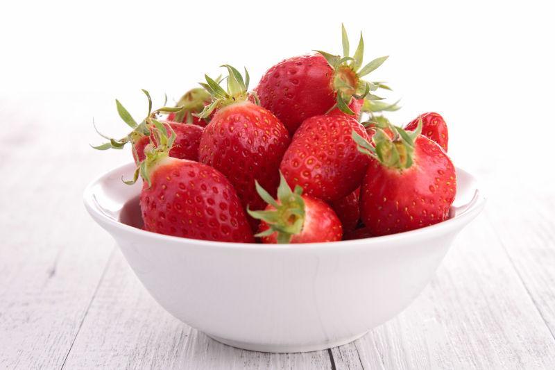 木桌上白色碗里的草莓