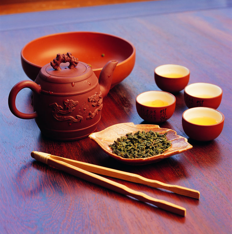 红木桌上的茶叶和红色茶壶