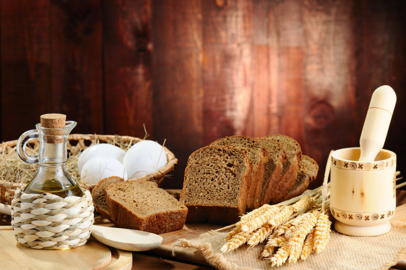 木桌上的切片面包与小麦