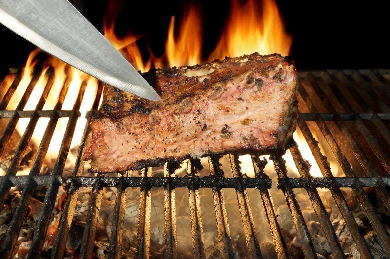 明亮的火焰背景下的厨师刀在烤肉剁碎