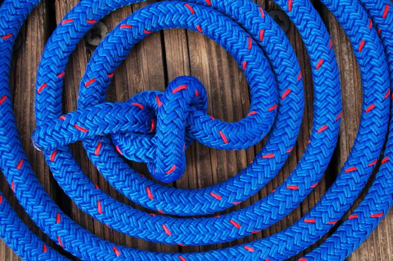 蓝红斑驳的绳索盘绕结船停靠码头