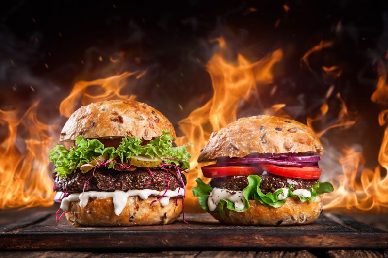木桌上火焰背景前的两个汉堡包