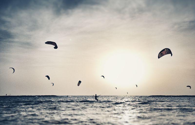 日落十分的很多海上风筝冲浪的人