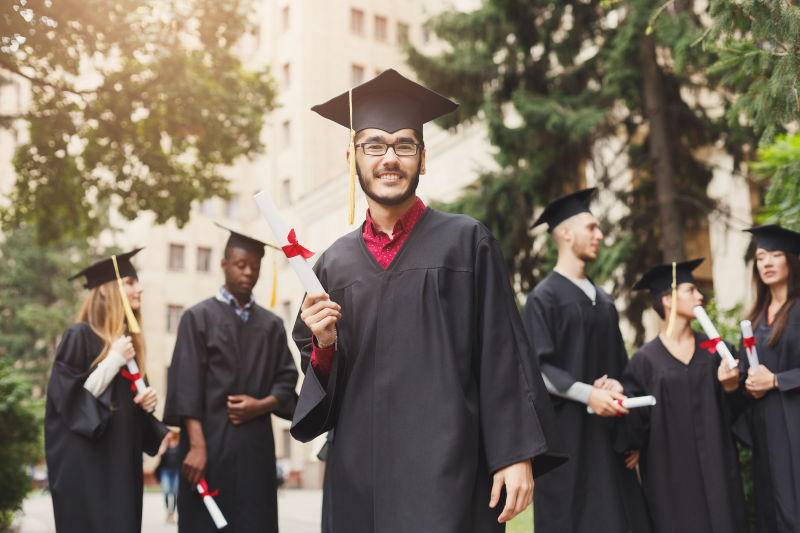 学校背景中穿毕业服拿文凭的学生们