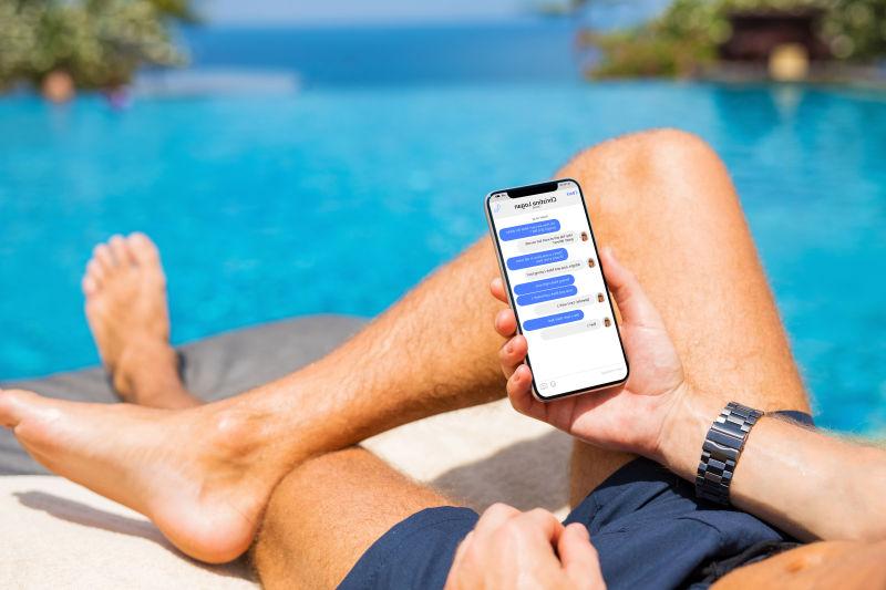 蓝色海边躺在沙滩椅上玩手机的人