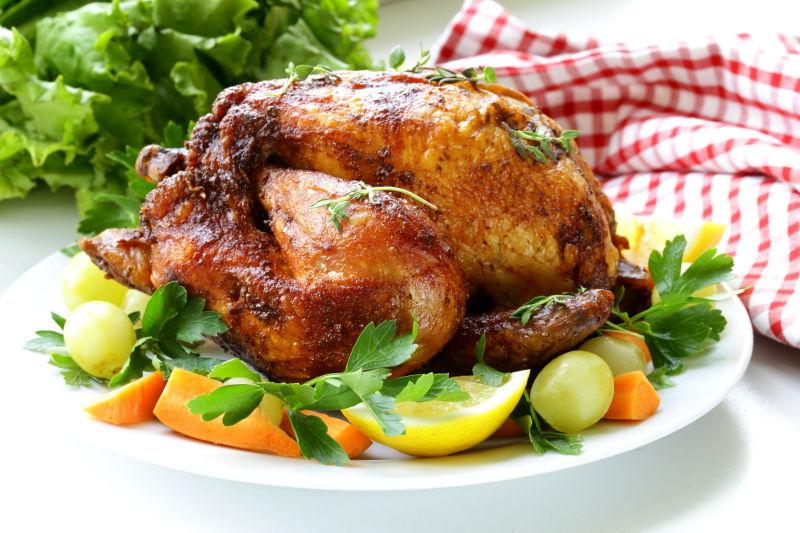 放在餐盘中的香喷喷的烤鸡和装饰蔬菜