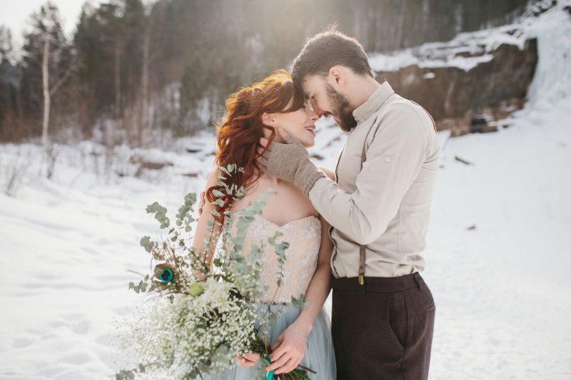 雪地上漂亮的新娘和新郎拥抱
