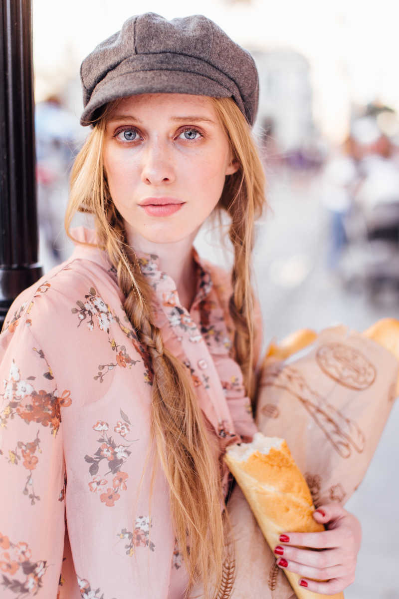 年轻的模特站在街上拿着面包