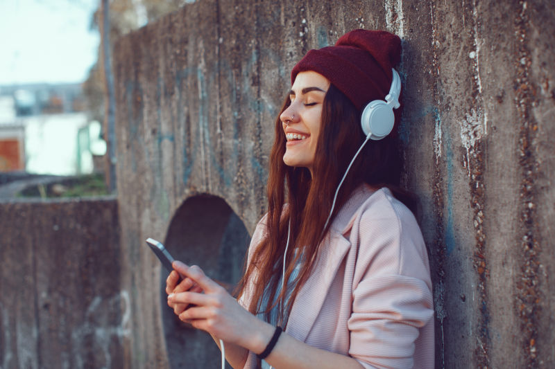 年轻的都市女性通过耳机和智能手机听音乐