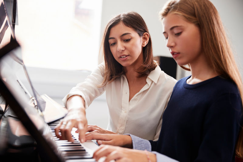 音乐课女学生与老师弹钢琴