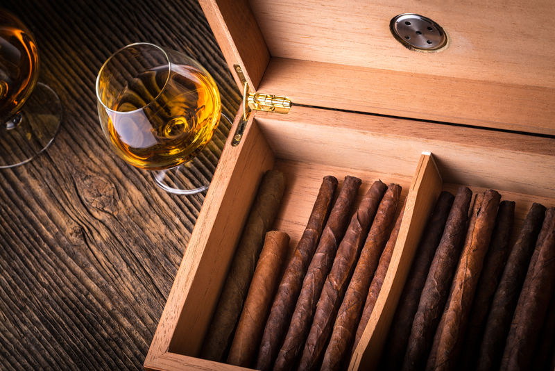 旧木桌上有雪茄和干邑白兰地的雪茄盒