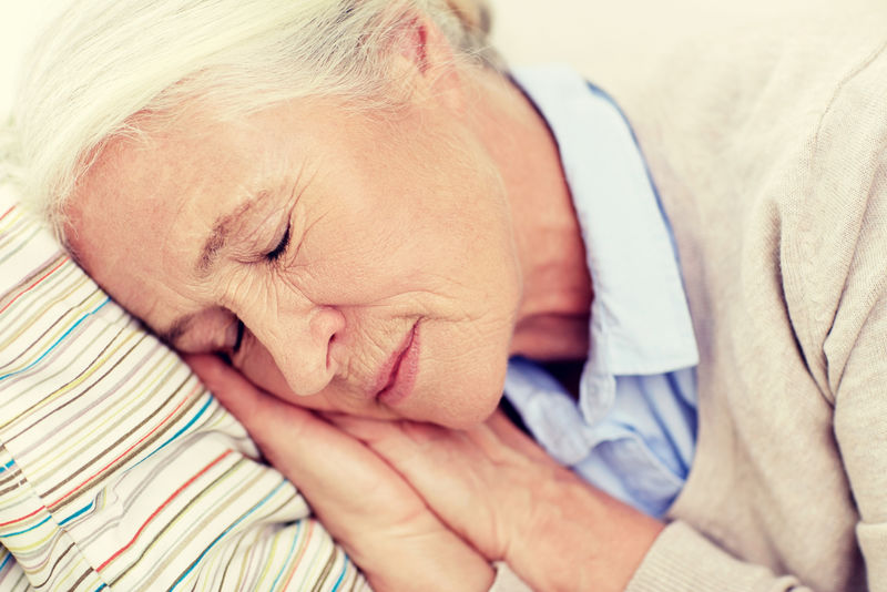 在家里睡在枕头上的快乐老年妇女