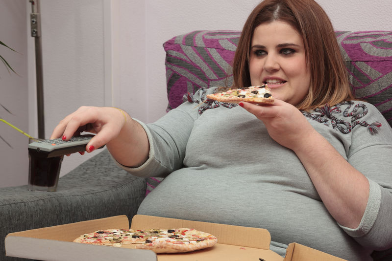 女人在沙发上吃披萨看电视