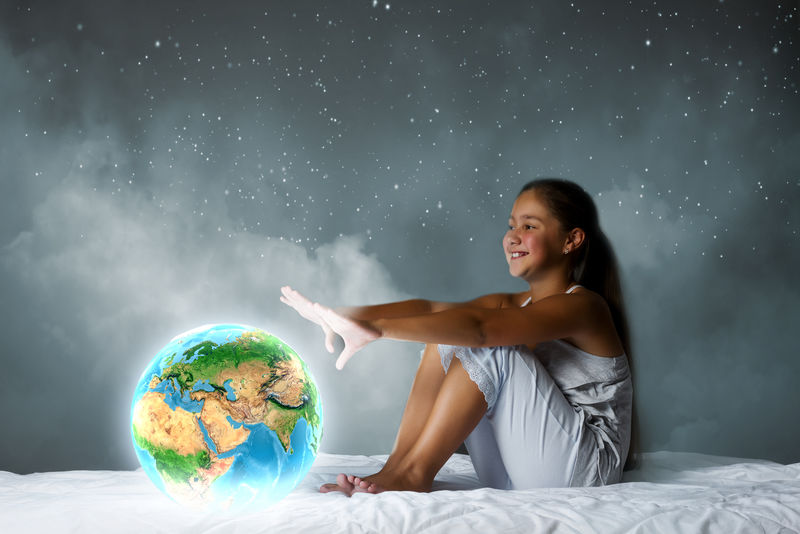 坐在床上看地球星球的可爱女孩-这幅图像的元素由美国宇航局提供