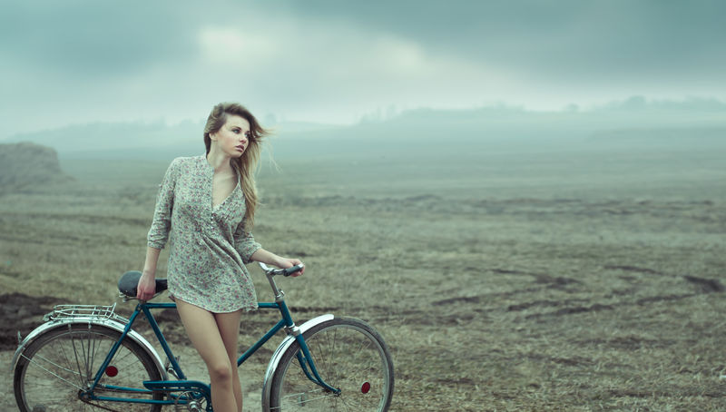 漂亮的女孩在自行车旁边休息