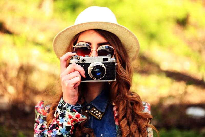 户外夏日生活写照美丽的年轻女子在城市里玩得很开心-摄影师戴着时髦的眼镜和帽子拍照-照片色调样式Instagram过滤器