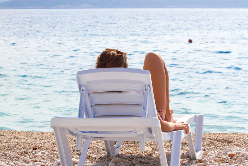 坐在躺椅上看着大海的女孩旅游娱乐