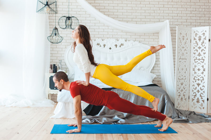 体育已婚夫妇正在家里练习瑜伽。
