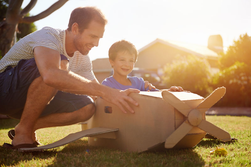 儿子和爸爸在家里的花园里玩玩具飞机-一起开心地笑着