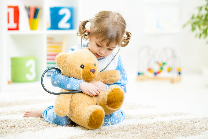 可爱的小女孩在家玩医生和毛绒玩具