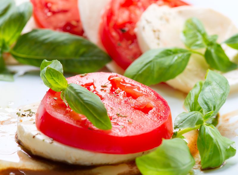 卡普雷色拉-番茄和马苏里拉片配罗勒叶-白色背景