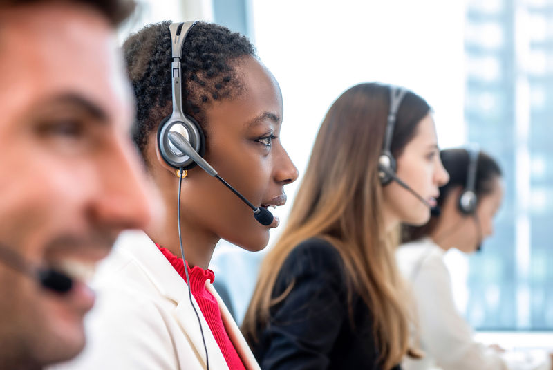 非裔美国女性电话营销客服人员在呼叫中心办公室与不同团队合作